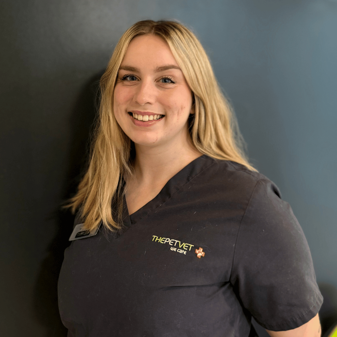 Female vet with long blonde hair in grey uniform stood against a grey wall